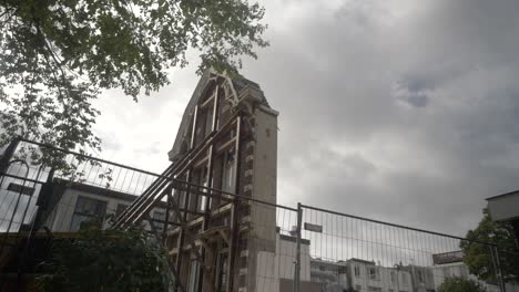 The-facade-of-a-classic-Amsterdam-building,-With-Trees-Swaying-in-the-Foreground-and-Cloudy-Skies