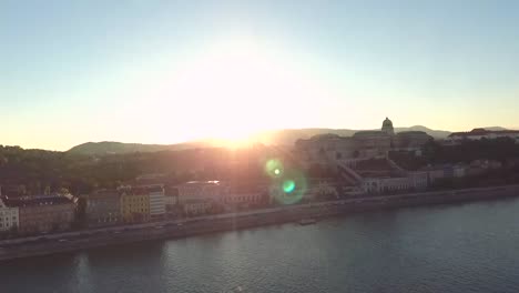 Puesta-De-Sol-Sobre-El-Lado-Del-Castillo-De-Buda,-Tomada-Desde-Un-Dron-Sobrevolando-El-Río-Danubio