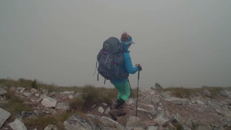 rocky-alpine-peaks,-landscape-of-a-slovakian-tatra-mountains,-female-hiker-walking-on-a-ridge,-camera-pan-from-left-to-right-with-a-person-to-reveal-a-distant-peak