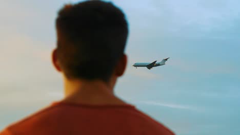 In-Diesem-Filmmaterial-Sehen-Sie-Ein-Profilbild-Der-Männlichen-Person,-Die-Das-Landende-Flugzeug-Am-Abendhimmel-Betrachtet