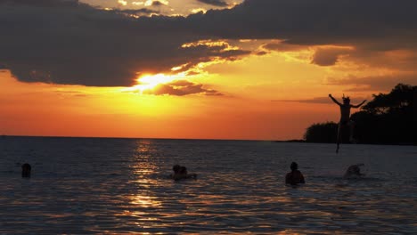 Family-having-fun-in-the-ocean-at-sunset,-and-playing-games