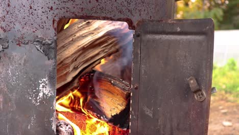 Kleines-Holzfeuer,-Das-Durch-Die-Tür-In-Einem-Fasskocher-Gesehen-Wird