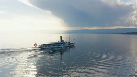 Siguiendo-Y-Acercándose-A-Un-Barco-De-Vapor-Belle-epoque-En-El-Lago-Léman---Suiza-Puesta-De-Sol,-Agua-Como-Un-Espejo-Y-Nubes-De-Tormenta-En-El-Fondo