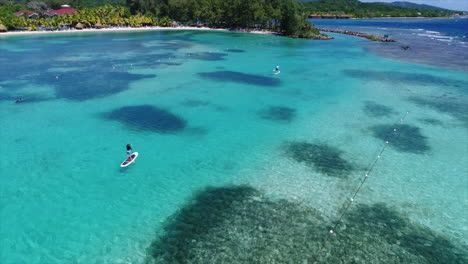 Aereal-view-of-people-paddleboarding-near-a-resortâ€™s-beach-on-the-Honduran-caribbean-sea