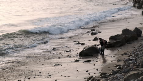 Orilla-Tranquila-De-La-Playa-De-Big-Rock,-Con-Un-Pescador-Profesional-Recuperando-Una-Caña-De-Pescar