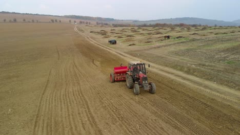 Tractor,-agricultural-machinery-and-workers-sow-a-field---aerial-tracking-shot