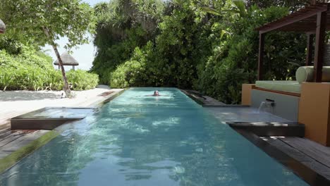 Young-woman-swims-laps-in-a-long-private-pool-at-a-luxury-resort-in-the-Maldives