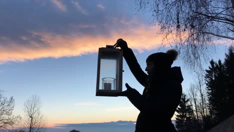 A-woman-lifts-up-the-lantern-with-a-candle,-early-in-the-morning