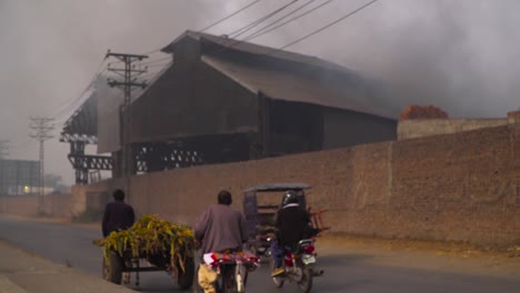 Industrial-pollution-is-effecting-the-population,-Traffic-is-going-on-with-the-factory,-Electric-polls-and-cables-at-the-road