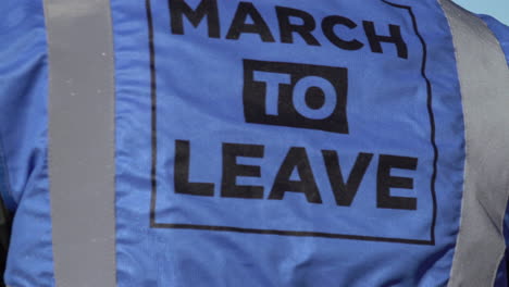 Un-Hombre-Viste-Un-Tabardo-Azul-Con-El-Logotipo-De-La-Marcha-Para-Irse-Del-Grupo-De-Campaña-Irse-Significa-Irse