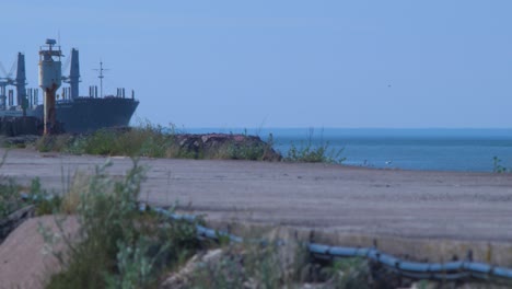 Bosque---Barco-De-Transporte-De-Productos-Que-Llega-Al-Puerto-De-Liepaja-En-Un-Caluroso-Día-De-Verano,-Tiro-Medio-Distante-Desde-El-Muelle-De-Fort