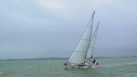 Segelschiff-Yacht-Mit-Französischer-Flagge,-Die-In-Brechenden-Wellen-Segelt-Und-Vorbeiheilt