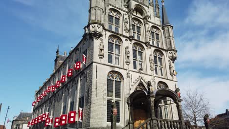 Ciudad-De-Gouda-En-Los-Países-Bajos,-Het-Oude-Stadhuys-En-El-Mercado-Con-Cielo-Azul-Y-Algunas-Personas