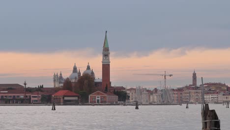 Puesta-De-Sol-Dorada-Del-Gran-Canal-De-Venecia-Con-Barcos-Y-Embarcaciones-Cruzando-Y-El-Museo-De-Arte-Punta-Della-Dogana-Al-Fondo