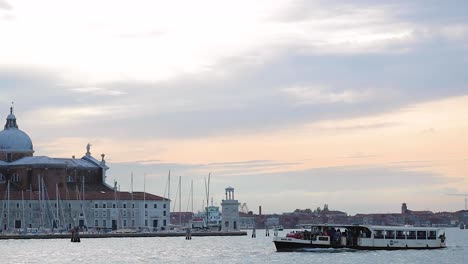 Toma-De-Seguimiento-De-Un-Barco-Pasando-Por-La-Iglesia-De-San-Giorgio-Maggiore-En-Venecia,-Italia-Al-Amanecer.