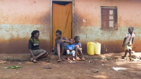 A-family-of-African-women-and-children-laughing-and-talking-outside-their-small-house-in-a-rural-African-village