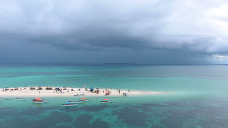 Nubes-Oscuras-Sobre-La-Isla-De-Arena-Tropical-Con-Gente-Y-Barcos