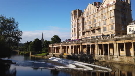 Lapso-De-Tiempo-De-Pulteney-Weir-Y-El-Hotel-Empire-En-Bath,-Somerset-En-La-Hermosa-Mañana-De-Verano-Con-Cielo-Azul-Y-Luz-Dorada