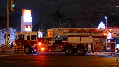 Toma-Amplia-Del-Camión-De-Bomberos-Del-Departamento-De-Bomberos-Con-Luz-Intermitente-En-El-Estacionamiento-Nocturno-Frente-A-La-Estación-De-Servicio,-Canadá