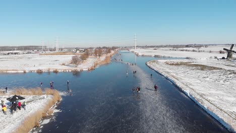 Patinadores-Sobre-Hielo-En-El-Canal-Congelado-De-Holanda-En-El-Campo-Holandés,-Vista-Aérea-De-Invierno