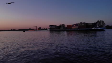 Friendship-Container-Vessel-Transporting-Cargo-At-Dusk-In-Oude-Maas-River-Near-Puttershoek,-South-Holland,-Netherlands