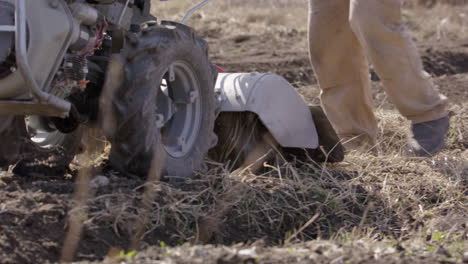 A-rototiller-being-used-by-a-man-to-work-the-land,-agriculture,-medium-shot