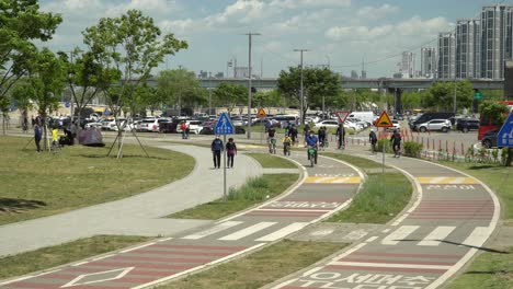 Korean-People-Biking-And-Walking-Near-The-Park-Along-Han-River-During-Pandemic-In-Seoul,-South-Korea