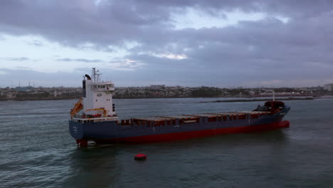 Aerial-circling-over-swaying-cargo-ship-near-Sans-Souci-port,-Santo-Domingo