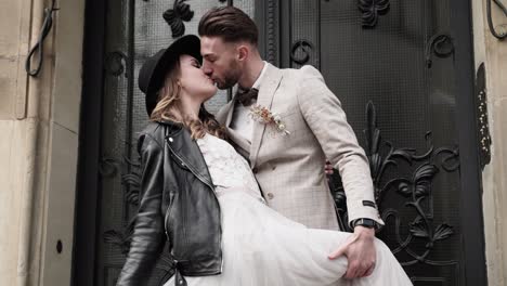 Pareja-De-Bodas-De-Estilo-Retro-Con-Besos-Apasionados-Frente-A-La-Puerta-Barroca---Novia-Con-Chaqueta-De-Cuero-Negro-Y-Sombrero-En-Cámara-Lenta