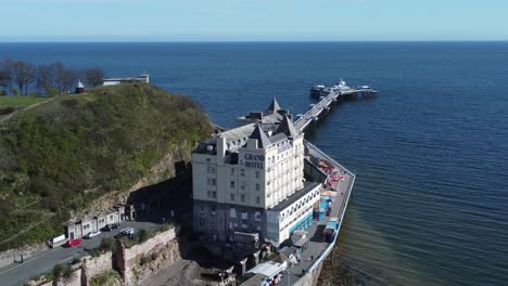 Aerial-view-of-The-Grand-hotel-landmark-Llandudno-seafront-seaside-Victorian-promenade-tourism-building-slow-descend