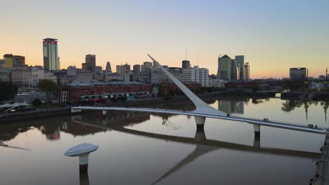 Luftaufnahme,-Die-Bei-Sonnenuntergang-Auf-Die-Frauenbrücke-Am-Ufer-Von-Puerto-Madero-Zufliegt