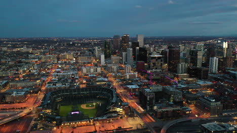 Vista-Aérea-Cinematográfica-Del-Centro-De-Denver-Por-La-Noche,-El-Estadio-De-Béisbol-Coors-Field-Y-El-Distrito-Financiero-Central,-Colorado,-Ee.uu.