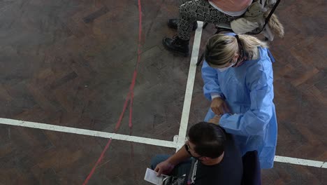 High-angle-view-of-a-nurse-applying-a-shot-of-COVID-vaccine-to-a-man-in-a-makeshift-vaccination-center