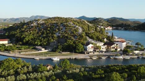 Eine-Luftaufnahme-An-Einem-Sommerabend-Nach-Der-Flussgabelung-Und-Öffnung-Von-Dorfhäusern-Mit-Angedockten-Booten-In-Rogotin,-Südkroatienküste