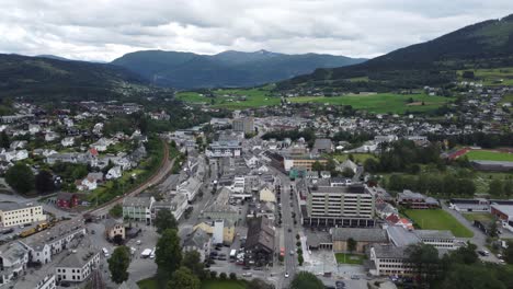 Stadtzentrum-Von-Voss-–-Luftaufnahme-Der-Hauptstraße-Mit-Gebäuden-Und-Geschäften-–-Eisenbahn-Auf-Der-Linken-Seite-Und-Berge-In-Der-Ferne-–-Norwegen