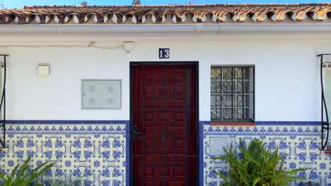 Orange-trees-in-a-typical-little-narrow-Spanish-street-with-houses-in-Marbella-old-town,-sunny-day-and-blue-sky-in-Spain,-4K-panning-left