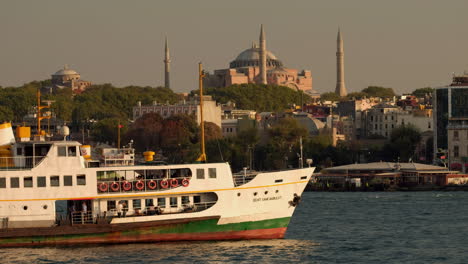 Teleaufnahme,-Statischer-Clip-Der-Alten-Istanbuler-Fähre,-Die-Bei-Sonnenuntergang-In-Istanbul-Langsam-An-Der-Hagia-Sophia-Vorbeifährt