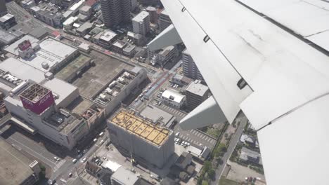 POV-Eines-Passagiers,-Der-Gebäude-Durch-Das-Fenster-Eines-Flugzeugs-Betrachtet,-Das-In-Der-Stadt-Tokio-In-Japan-Fliegt