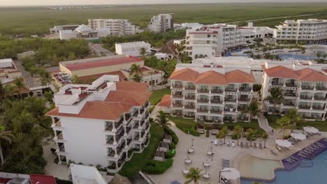 AERIAL---A-hotel-and-its-swimming-pool-in-Cancun,-Mexico,-spinning-shot