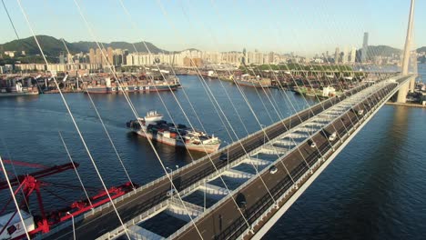 Large-Container-Ship-leaving-Hong-Kong-bay-under-Stonecutters-bridge,-Aerial-view