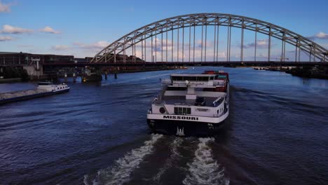 Luftaufnahme-Des-Hecks-Eines-Missouri-Containerschiffs,-Das-Unter-Der-Brücke-Am-Fluss-Noord-Vorbeifährt