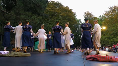 Erwachsene-Kaukasische-Tänzerinnen-In-Traditionellen-Volkskostümen-Treten-Bei-Einer-Tanzvorstellung-Unter-Freiem-Himmel-Auf,-Sonniger-Sommerabend,-Fröhliche,-Lettische-Nationalkultur,-Weite-Handaufnahme-Aus-Der-Tiefwinkelansicht