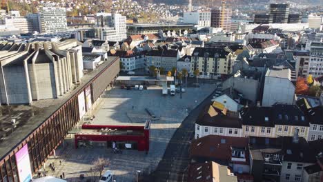 Town-square-outside-concert-hall-Grieghallen-in-Norway---Low-altitude-aerial-above-street-and-concert-house---Autumn-sunset-light