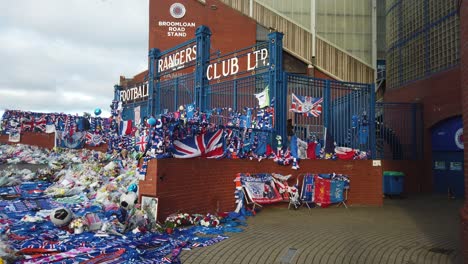 Eine-Seitliche-Totalaufnahme-Von-Fußballfans,-Die-Vor-Dem-Haupttor-Des-Rangers-FC-Dem-Ehemaligen-Manager-Walter-Smith-Tribut-Zollen