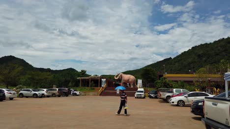 A-wide-shot-from-the-car-park-area-capturing-a-giant-elephant-sculpture-in-distance-at-Luang-Pu-Thuat-compound-on-a-hot-sunny-weather-in-Phuttha-Utthayan-Maharat-Ayutthaya-Thailand