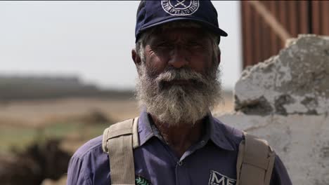 Anciano-Trabajador-Pakistaní-Con-Barba-Blanca-Con-Gorra-De-Béisbol-Mirando-A-La-Cámara