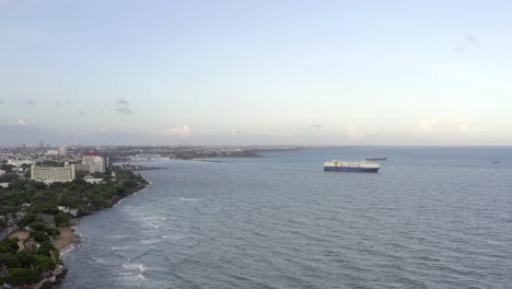 Drone-Volando-Sobre-El-Mar-Y-El-Buque-De-Carga-En-El-Fondo-Cerca-Del-Malecón,-Santo-Domingo