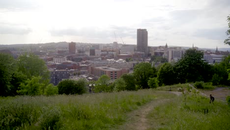 Stabilisierte-Kardanische-Aufnahme-Eines-Mannes-Mit-Rucksack-Und-Kamera,-Der-Vom-Sheaf-Valley-Park-Aus-Fotos-Von-Der-Skyline-Von-Sheffield-Macht