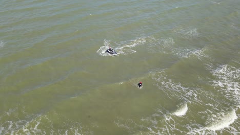 Imágenes-Aéreas-De-Un-Hombre-En-Una-Moto-De-Agua,-Otro-Vadeando-Hacia-La-Orilla