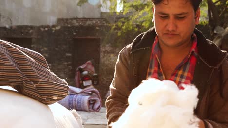 Man-working-outside-filling-pillow-at-Indian-cotton-market-shop-of-Indian-village-in-Rajasthan